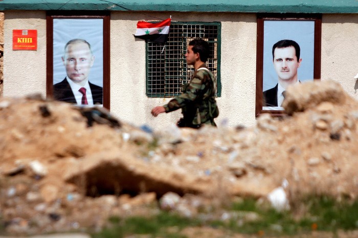 Binh sĩ chính quyền Syria đi ngang qua khu nhà có hình ảnh Tổng thống Nga Vladimir Putin và Tổng thống Syria Bashar al Assad ở khu vực Đông Ghouta vừa được quân đội Syria giải phóng - Ảnh: REUTERS