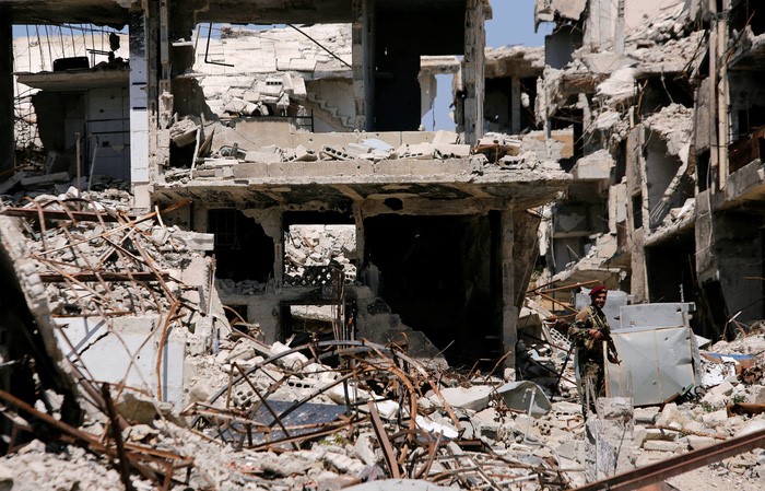 Binh sĩ quân đội chính phủ Syria (góc phải) canh gác vào ngày 2/4 ở trước những căn nhà đã bị bom đạn phá tan nát tại thị trấn Jobar, thuộc khu Đông Ghouta ở ngoại ô thủ đô Damascus từng bị lực lượng nổi dậy chiếm đóng trong thời gian dài - Ảnh: REUTERS