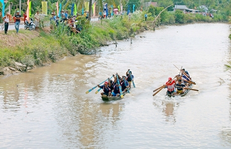 Thi đấu đua xuồng tam bản nam được đông đảo người xem cổ vũ dọc bờ sông.