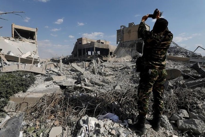Một sĩ quan quân đội Syria đang ghi hình cảnh tượng đổ nát bên trong Trung tâm Nghiên cứu Khoa học ở Damascus. Ảnh: Reuters.