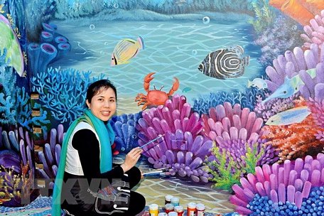 Họa sỹ Nguyễn Thu Thủy bên tác phẩm gắn gốm nghệ thuật Nhà Gương. (Ảnh: Đinh Thuận/TTXVN)