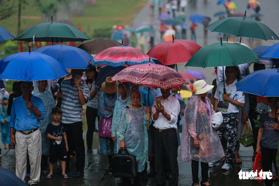 Rất đông người dân có mặt từ sớm và đứng dưới mưa chờ - Ảnh: NAM TRẦN