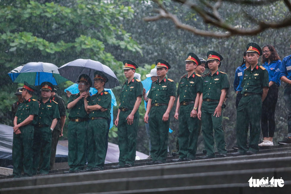 Hàng rào an ninh đứng dưới mưa để đảm bảo an ninh trật tự - Ảnh: NAM TRẦN