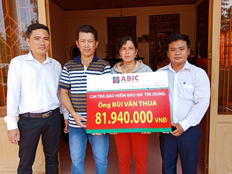 Ông Võ Văn Hoàng- đại diện ABIC (phải)- và ông Nguyễn Trung Tín- đại diện Agribank TX Bình Minh (trái)- trao biểu trưng cho gia đình khách hàng.