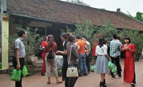 Du khách thích thú sở hữu sản phẩm sau khi trải nghiệm gói bánh chưng trong ngôi nhà cổ trăm tuổi tại làng cổ Hùng Lô, Phú Thọ.