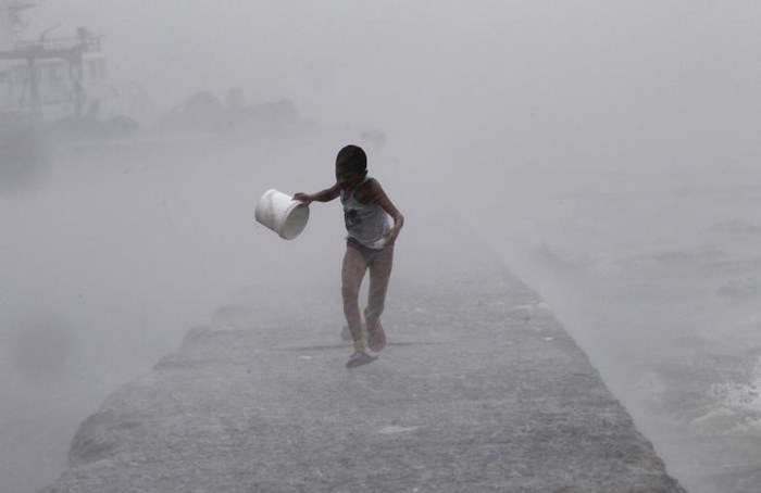 Một cậu bé chạy dưới trời mưa tầm tã khi những con sóng lớn liên tục vỗ vào bờ trong cơn bão Linfa ở Vịnh Manila, Philippines ngày 6/7/2015.