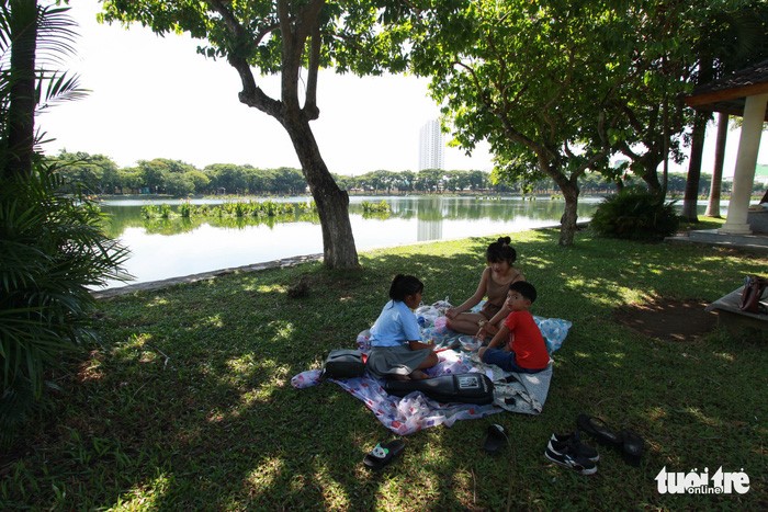 Nhiều gia đình mang bạt ra công viên 29/3 ngồi tránh... nóng - Ảnh: TẤN LỰC