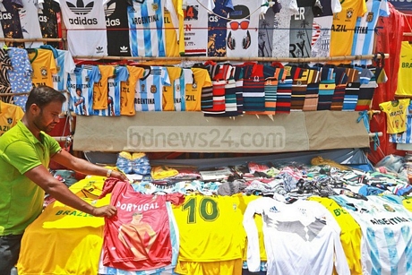 Một người đàn ông cầm chiếc áo thể thao có in hình danh thủ Cristiano Ronaldo và dòng chữ Bồ Đào Nha tại một sạp bán quần áo ở Bangladesh - Ảnh: TWITTER