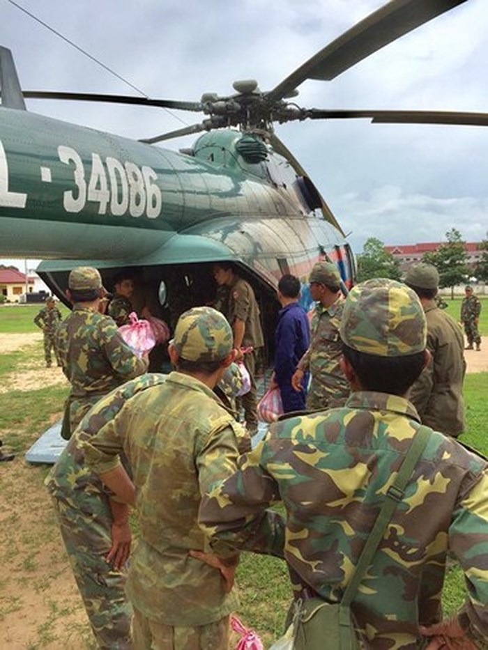 Các nhân viên cứu hộ đang vận chuyển hàng cứu trợ từ trực thăng ra ngoài. Ảnh: ABC Laos.