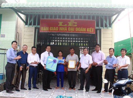 Ông Huỳnh Trung Phong (đứng bên phải)- Phó Chủ tịch UBND phường Cái Vồn trao quyết định bàn giao nhà cho hộ bà Thạch Thị Sót.