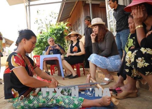 Khách tham quan tìm hiểu về nghề dệt thổ cẩm của người dân tộc K’Ho. Ảnh: Nguyễn Dũng/TTXVN
