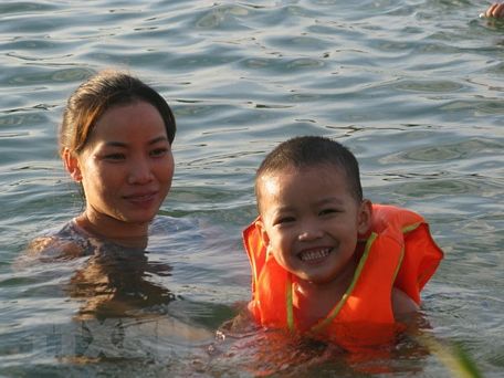 Không chỉ người lớn, trẻ em cũng được mang ra sông tắm vì nắng nóng. (Ảnh: Thanh Hải/TTXVN)