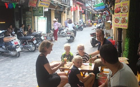 Nhiều khách du lịch quốc tế tìm đến Việt Nam vì mê phong cảnh thiên nhiên, ẩm thực, văn hóa truyền thống... (Ảnh: Khách nước ngoài thưởng thức món ăn Việt Nam tại phổ cổ Hà Nội.