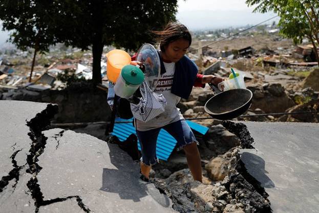 Tính đến nay, thảm họa kép ở Indonesia đã khiến hơn 1.550 người thiệt mạng cùng hàng vạn ngôi nhà bị phá hủy. Trong ảnh là một cô gái với khuôn mặt nhem nhuốc và mệt mỏi đang cố gắng lượm lặt lại những gì còn có thể sử dụng được trong ngôi nhà đổ nát của mình ở quận Balaroa, thành phố Palu. Ảnh: Reuters