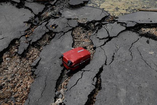  Một chiếc va li nằm trơ trọi trên con đường đã bị trận động đất phá hủy tan hoang ở quận Balaroa. Ảnh: Reuters