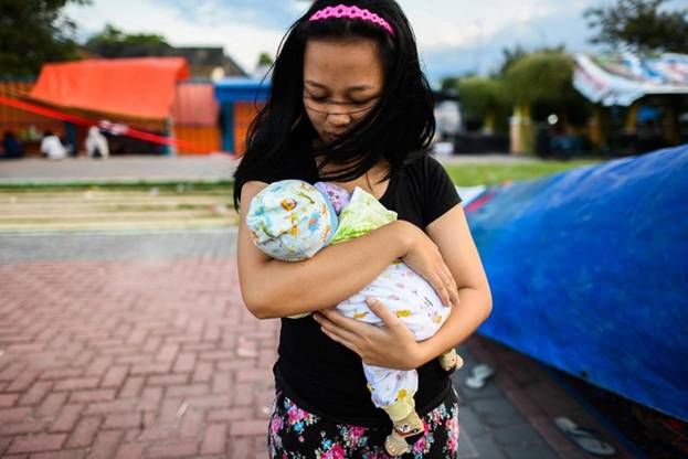  Người phụ nữ còn sống sót sau thảm họa ở Indonesia ôm chặt lấy cậu con trai bé nhỏ 2 tháng tuổi trong vòng tay. Ảnh: AFP./.