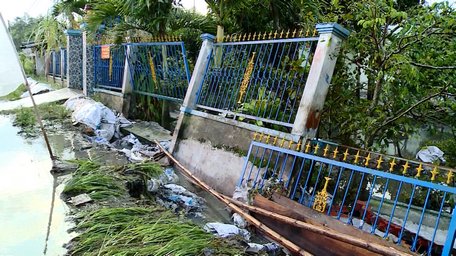 Nước tràn làm lở đường và hàng rào trước nhà bà Tống Thị Duyên (ấp Hòa Hưng xã Hòa Phú) bị sập hoàn toàn.