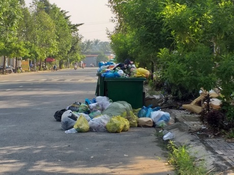 Những thùng rác nằm dọc dưới lòng đường. Những thùng rác này đã “no” rác và những bịch rác tràn ra đường 