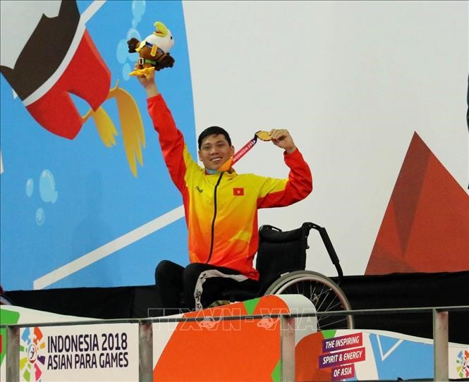 VĐV Võ Thanh Tùng tự hào giơ cao tấm Huy chương vàng thứ 3 tại Asian Para Games 2018. Ảnh: Hải Ngọc/TTXVN