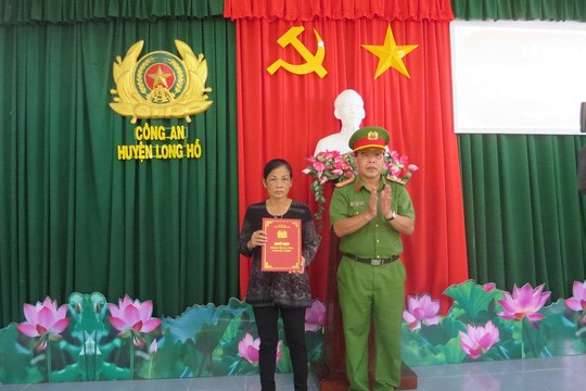Đại tá Trần Văn Thắng, Trưởng Công an huyện Long Hồ, trao quyết định cho bà Tươi về việc thăng quân hàm cho trung úy Nguyễn Đức Đạt.