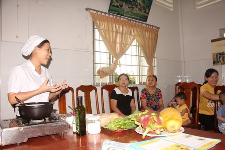 Nhân viên Trạm Y tế Phường 1 (TP Vĩnh Long) hướng dẫn bà mẹ cách nấu một suất ăn (cháo) đảm bảo đủ 4 thành phần cho em bé.