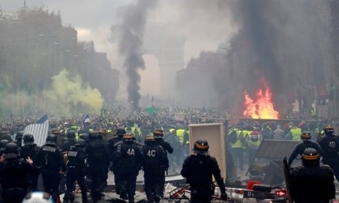 Người biểu tình mặc áo khoác vàng chạy khỏi cảnh sát trên đại lộ Champs-Elysees ở Paris hôm 1/12. Ảnh: Reuters