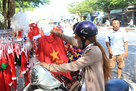 Cờ, áo, băng rôn… được bán nhiều tại các cửa hàng trên đường Nguyễn A4: Từ tối ngày 14/12, nhiều người hâm mộ đã chuẩn bị áo, cờ để cổ vũ cho trận đấu tối nay.