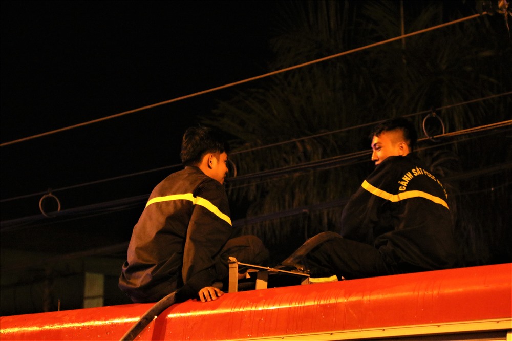 Hai chiến sĩ cảnh sát PCCC đang ngồi trò chuyện trên một xe tưới nước công trình đô thị sau khi đám cháy được dập tắt. Ảnh: Bảo Trung
