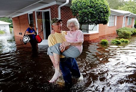 Bob Richling đưa bà Iris Darden, 84 tuổi, ra khỏi ngôi nhà bị ngập lụt sau bão Florence ở Spring Lake, North Carolina, Mỹ, phía sau là con dâu bà, Pam Darden, gom góp đồ đạc, ngày 17/9/2018. Ảnh: AP