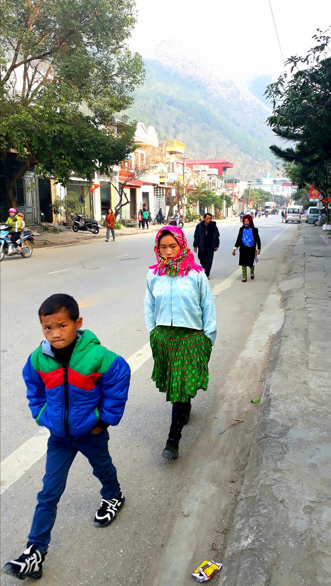 Trẻ con trong bộ trang phục sặc sỡ cùng bố mẹ xuống chợ.