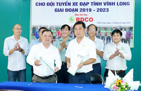 Ông Nguyễn Minh Hiền- Giám đốc Trung tâm Huấn luyện- thi đấu TDTT Vĩnh Long (trái) ký hợp đồng với nhà tài trợ mới cho xe đạp Vĩnh Long.