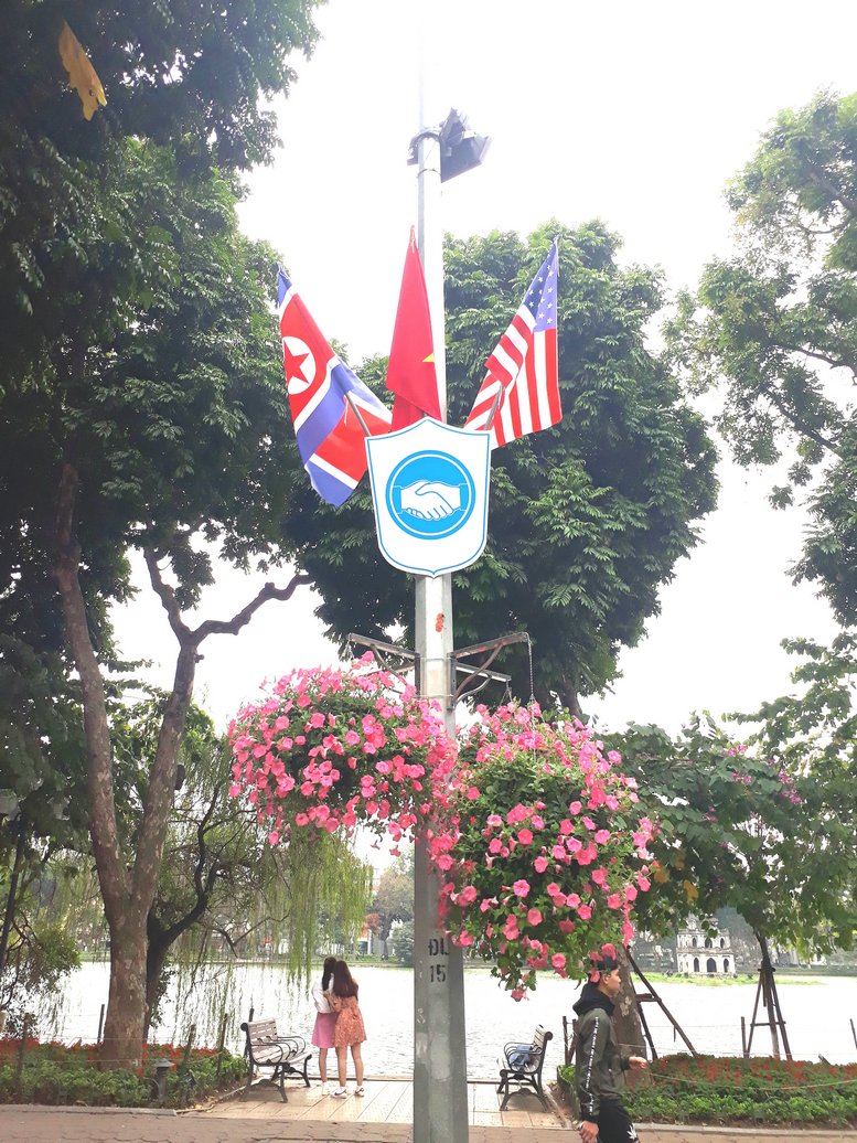 Biểu tượng bắt tay thể hiện thông điệp hòa bình của cuộc gặp gỡ giữa hai nhà lãnh đạo Mỹ - Triều Tiên xuất hiện cùng với quốc kỳ của hai nước và quốc kỳ Việt Nam treo dọc các tuyến phố.