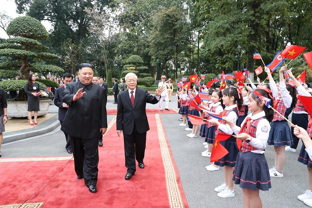   Tổng Bí thư, Chủ tịch nước Nguyễn Phú Trọng và Chủ tịch Triều Tiên Kim Jong-un vẫy tay chào thiếu nhi Hà Nội đón đoàn. (Ảnh: Trí Dũng/TTXVN)