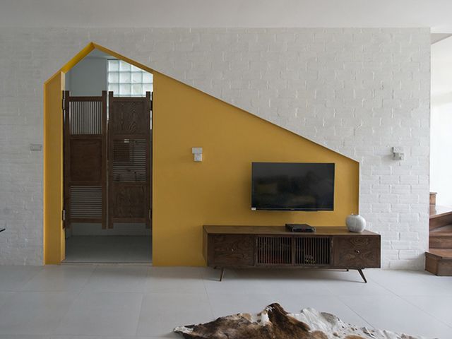 Góc đặt tivi và tủ ly được sơn màu vàng tạo điểm nhấn và phân tách không gian giúp tạo cảm giác rộng hơn.