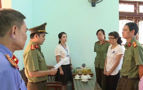 Bà Nguyễn Thị Hồng Nga, chuyên viên Phòng khảo thí và quản lý chất lượng Sở GD-ĐT Sơn La (mặc áo trắng bên phải), nghe tống đạt quyết định khởi tố bị can hôm 31/7/2018 - Ảnh: Công an cung cấp