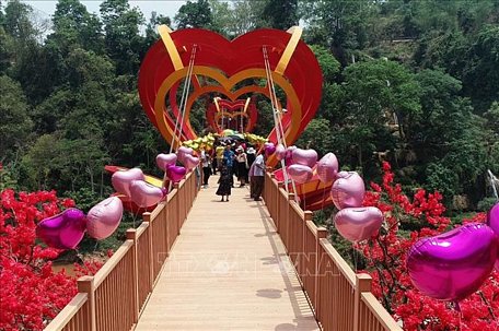 Du khách tham quan và trải nghiệm cầu kính tình yêu tại Khu du lịch sinh thái thác Dải Yếm, huyện Mộc Châu, tỉnh Sơn La. Ảnh: TTXVN phát
