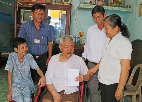 Ông Nguyễn Văn Thành- Chủ tịch UBMTTQ Việt Nam thị trấn Cái Nhum (đứng bên phải) cùng đại diện trường đến trao tiền hỗ trợ cho gia đình ông Võ Trung Hiếu.