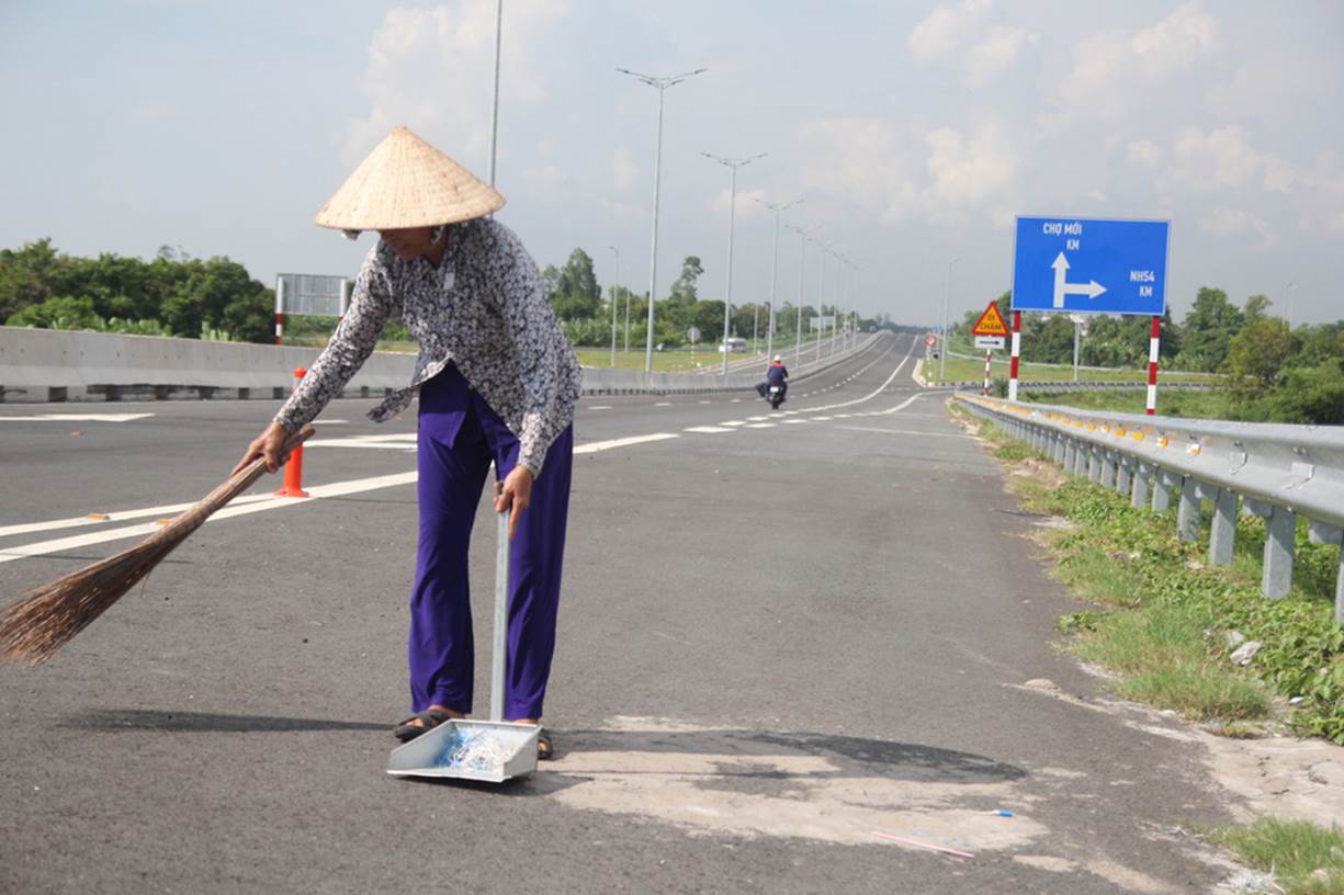 Một người dân được đơn vị thi công thuê dọn dẹp mặt cầu trước khi thông xe - Ảnh: MẬU TRƯỜNG