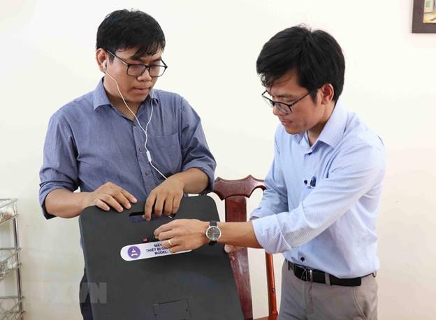  Thầy Tôn Thất Trường Nam (bên trái) và thầy Trần Quốc Lâm giới thiệu về máy phát hiện gian lận thi cử. (Ảnh: Phạm Cường/TTXVN)