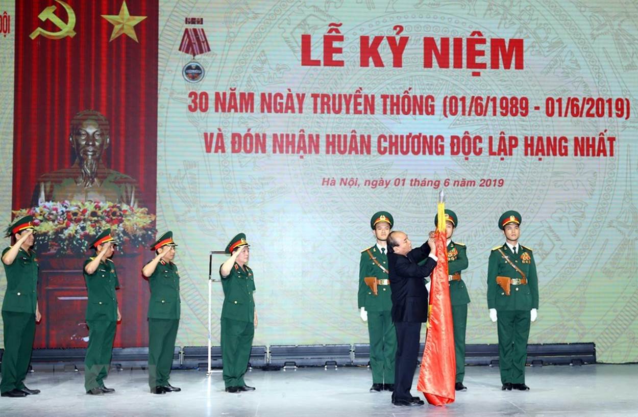Thủ tướng Nguyễn Xuân Phúc, thừa ủy quyền Chủ tịch nước gắn Huân chương Độc lập Hạng Nhất lên lá cờ truyền thống của Tập đoàn Công nghiệp-Viễn thông quân đội. (Ảnh: Thống Nhất/TTXVN)