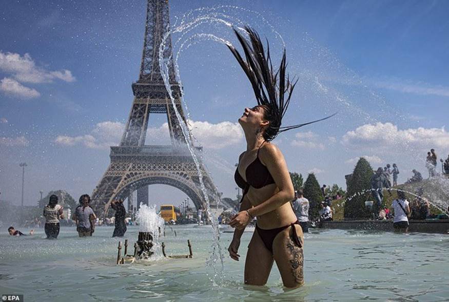 Một người phụ nữ đối phó với nắng nóng bằng cách ngâm mình trong nước tại một đài phun nước gần tháp Eiffel ở Paris - nơi nhiệt độ có thể lên tới 47 độ C. Ảnh: EPA