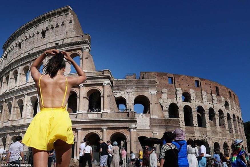 Một người phụ nữ đang buộc tóc cao trong khi đi bộ dưới bầu trời không một gợn mây ở Rome với nhiệt độ những ngày này có thể lên tới 38 độ C. Ảnh: AFP