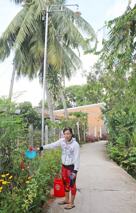 Chị Nguyễn Thị Bé Cưng chăm sóc bông hoa trước hàng rào nhà.