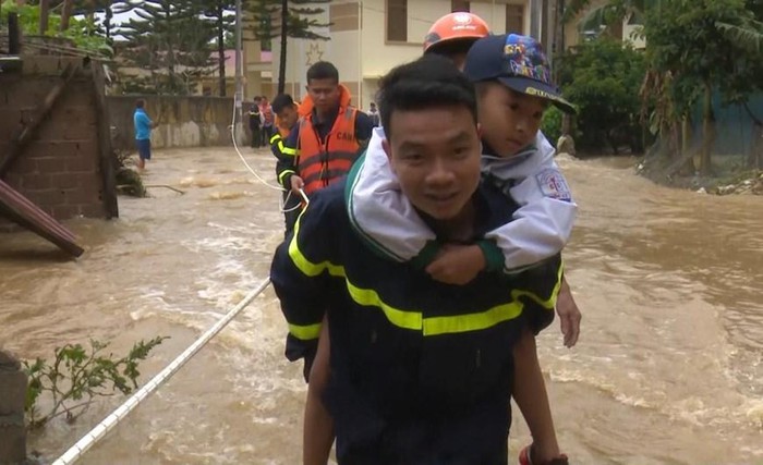 Lực lượng chức năng huyện Mộc Châu, tỉnh Sơn La hỗ trợ trẻ em qua khu vực đường bị ngập trong nước. (Ảnh: Nguyễn Cường/TTXVN)
