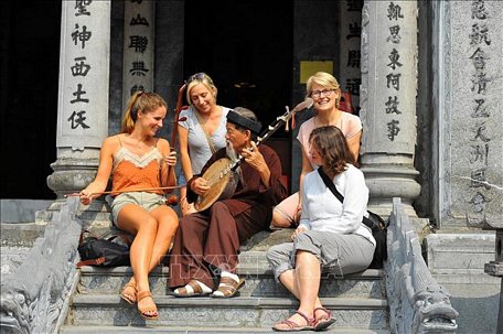 Du khách nước ngoài trải nghiệm chơi nhạc cụ dân tộc tại đền Thái Vi (Ninh Bình). Ảnh: Minh Đức/TTXVN