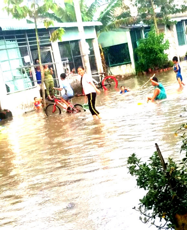 Nước ngập sâu một số nơi ở xã Mỹ Hòa, trẻ con ra đường chơi với nước.