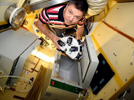 Nhà du hành vũ trụ người Nga Oleg Kononenko cầm một chiếc máy in 3D sinh học trên ISS - Ảnh chụp màn hình Bloomberg