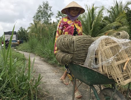 Người lao động nông thôn nhận khung nhựa, sợi lác về đan khung lác gia công cho công ty (ảnh chụp tại ấp Mỹ Định, xã Tân Mỹ).