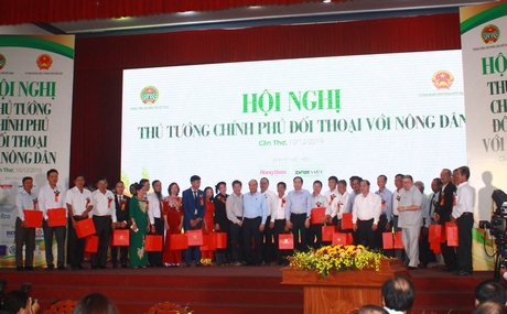 Thủ tướng Chính phủ Nguyễn Xuân Phúc (người đứng giữa) tặng quà các đại biểu nông dân nhân buổi đối thoại.