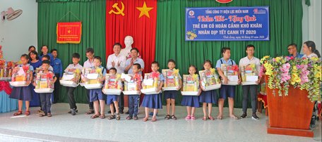 Đại diện lãnh đạo Tổng Công ty Điện lực Miền Nam (bên trái), Sở Lao động- Thương binh và Xã hội trao quà tết cho trẻ em nghèo.